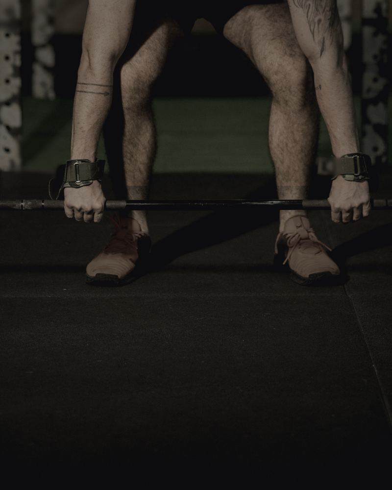 A man setting up a deadlift in a dim gym